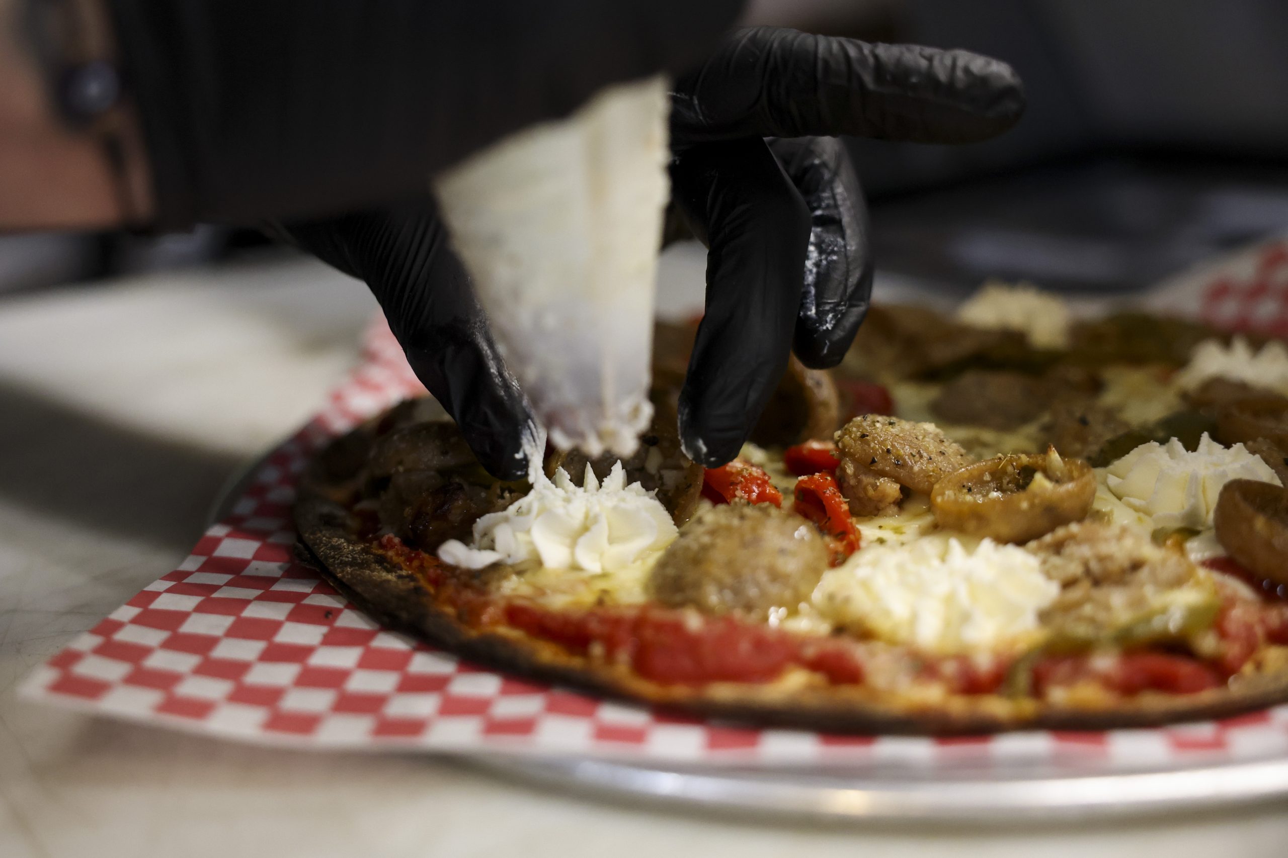 Michael Sundstrom pipes whipped ricotta cheese on a deluxe sausage...