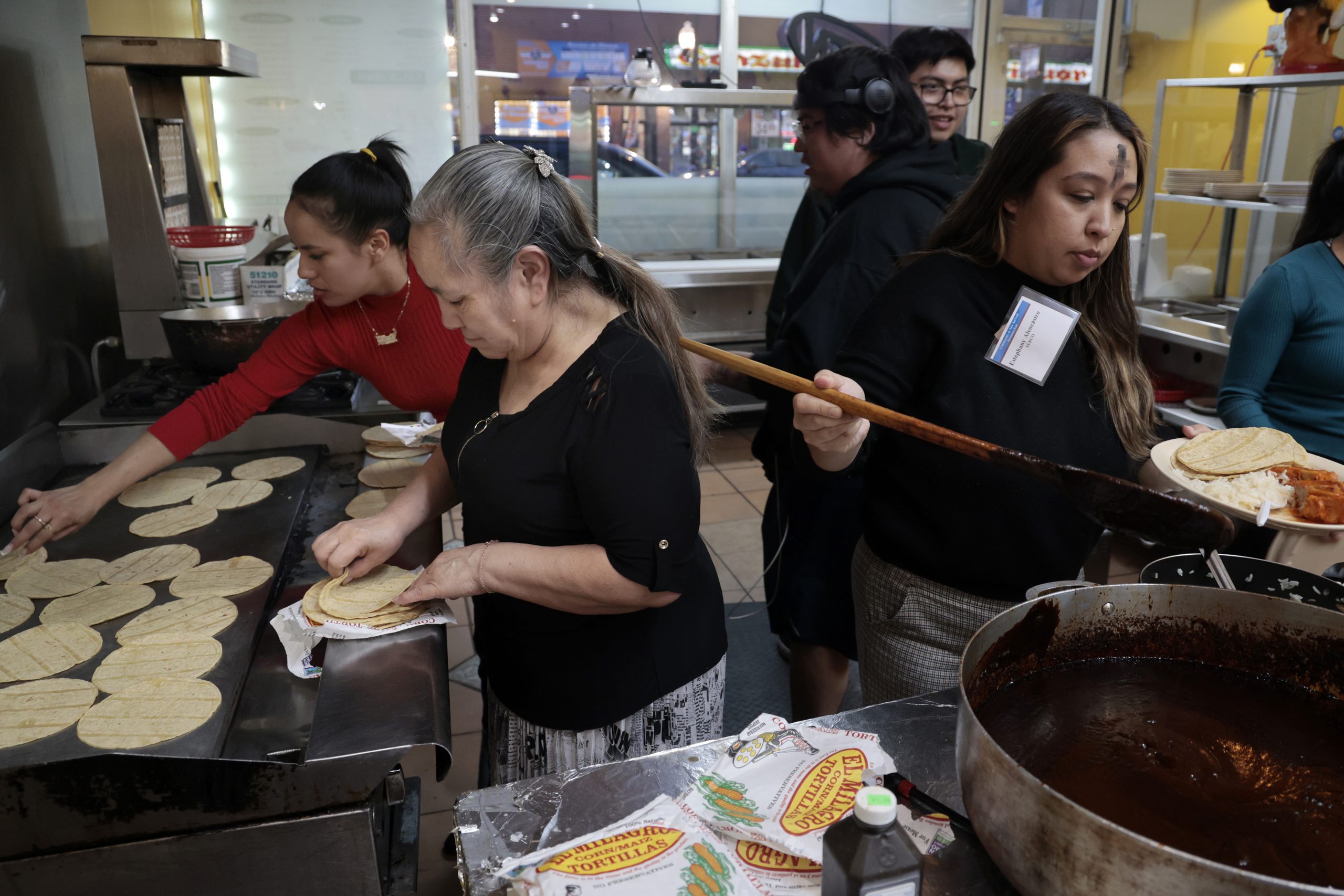 Claudia Perez helps heat up tortillas with daughter Elizeth, during...