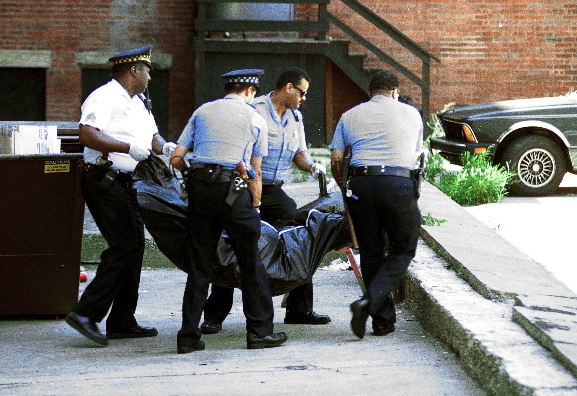 Chicago police officers remove the body of man from the...