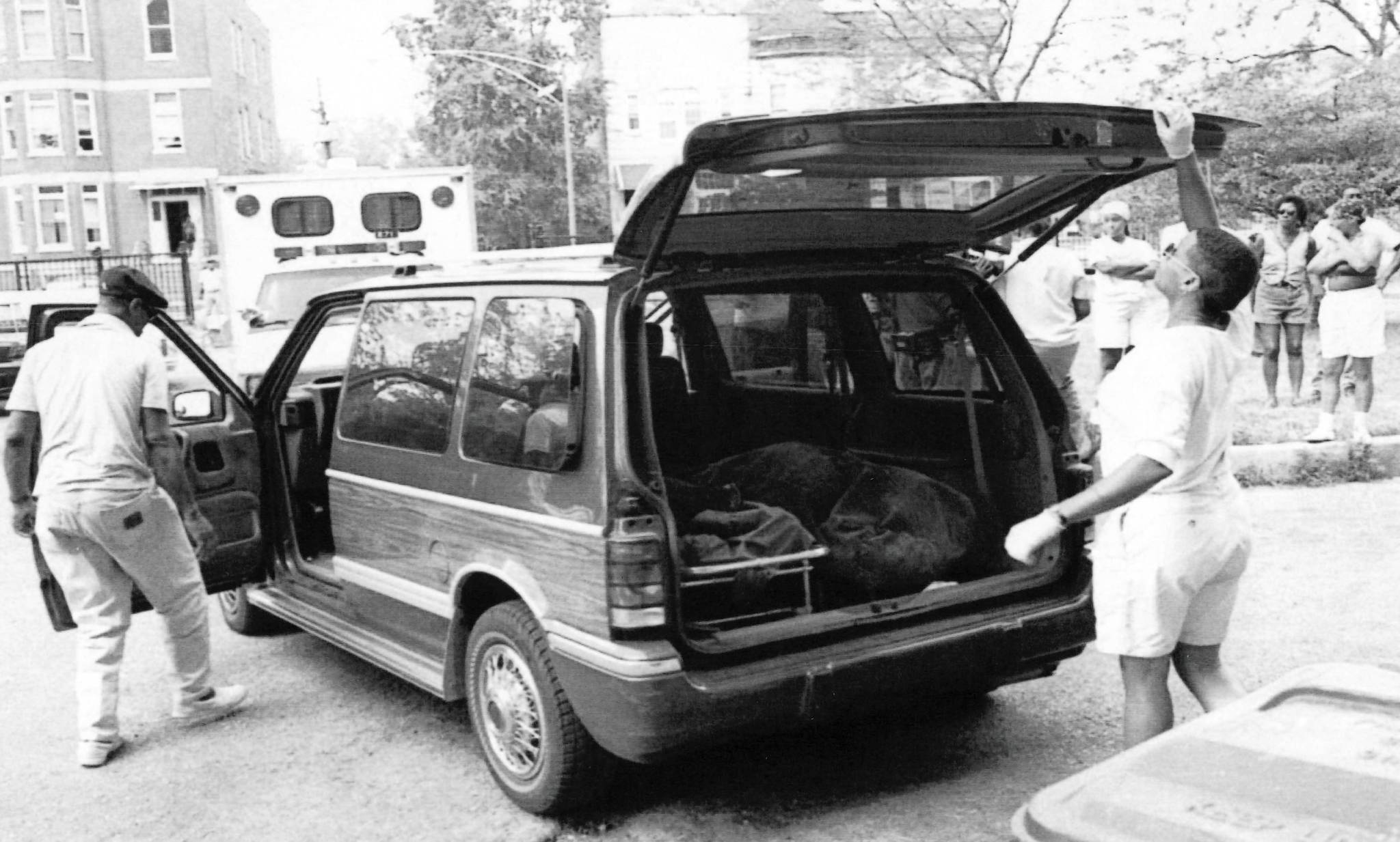 Funeral home employees load a woman's body into a minivan...