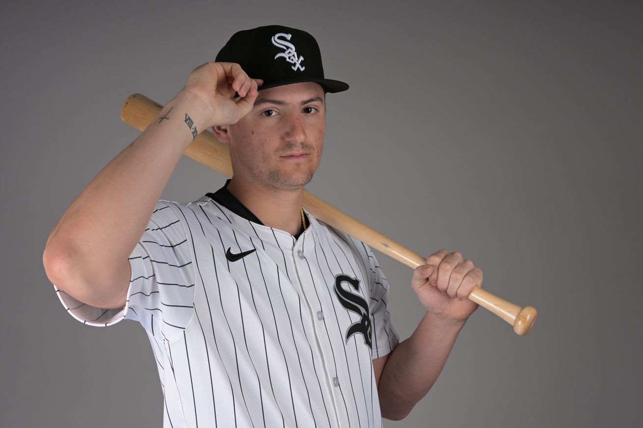 Chicago White Sox rookie shortstop Colson Montgomery (No. 83) poses for a photo on media day at the team’s spring training facility in Glendale, AZ. He holds a bat on his left shoulder and is tipping his cap to the camera with his right had, wearing a very serious expression.