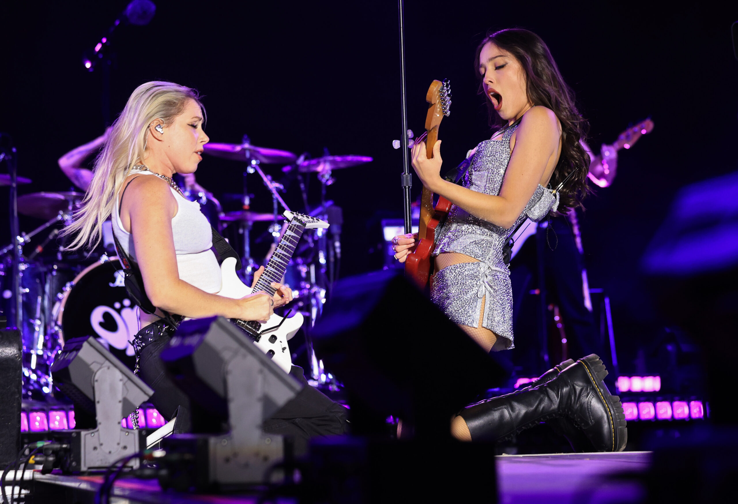 Olivia Rodrigo, right plays guitar with a band member while...