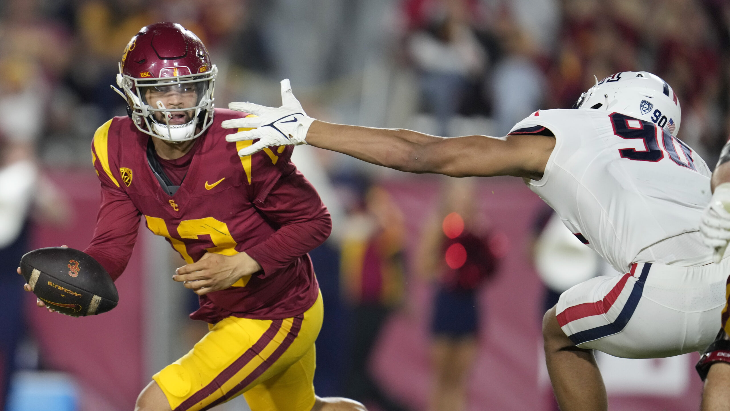 Southern California quarterback Caleb Williams, left, evades the tackle attempt...