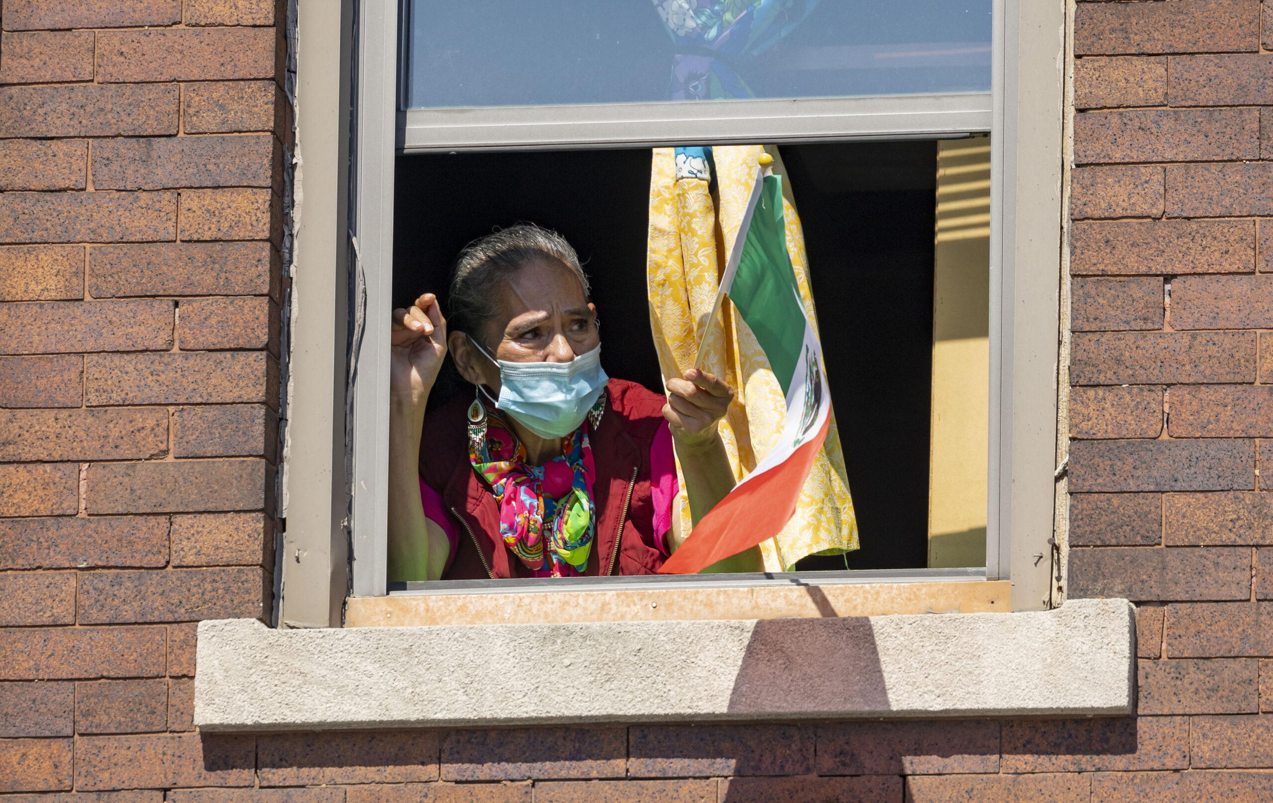 A woman watches from a window during the annual 26th...