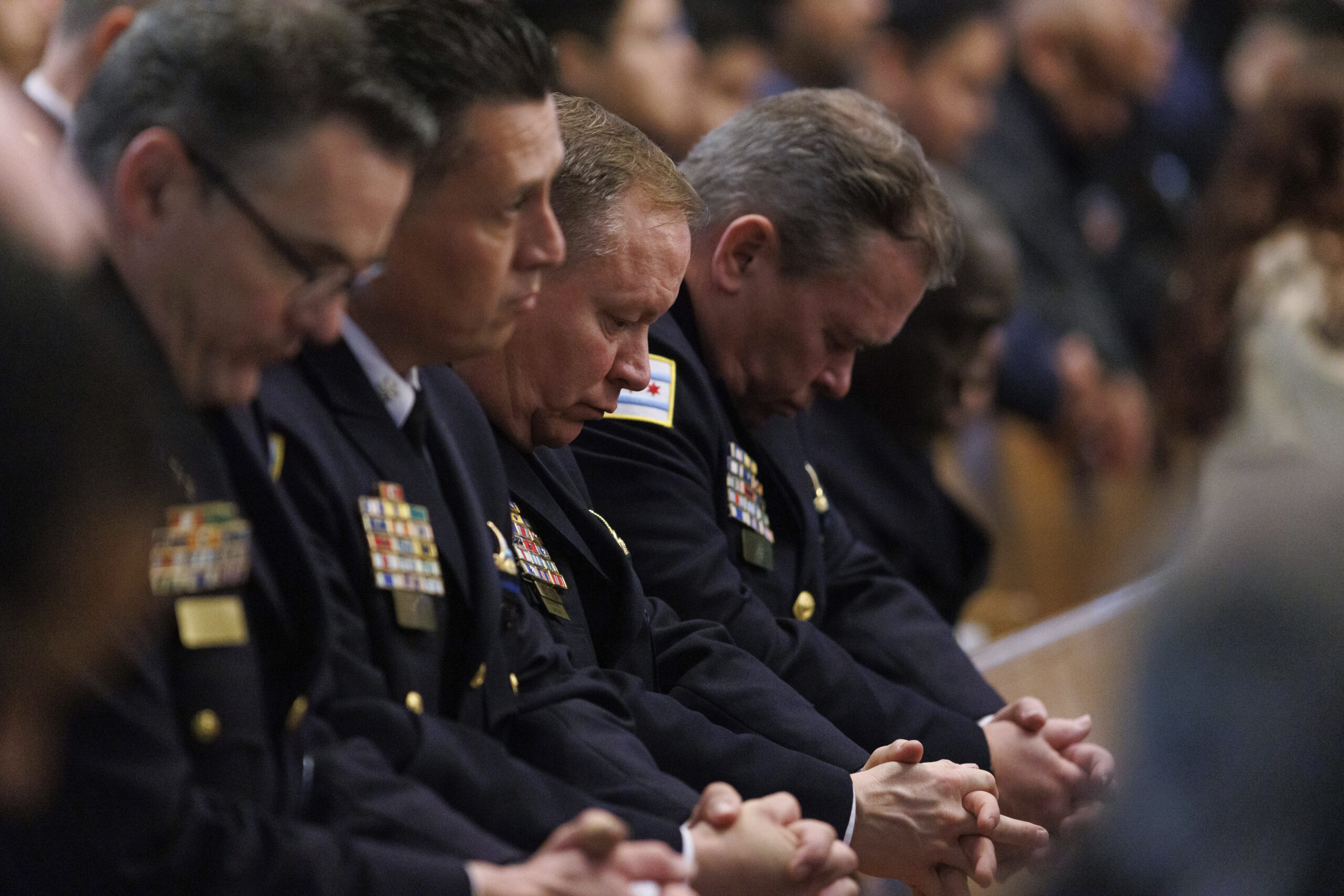 Police officers bow their heads during a prayer at funeral...