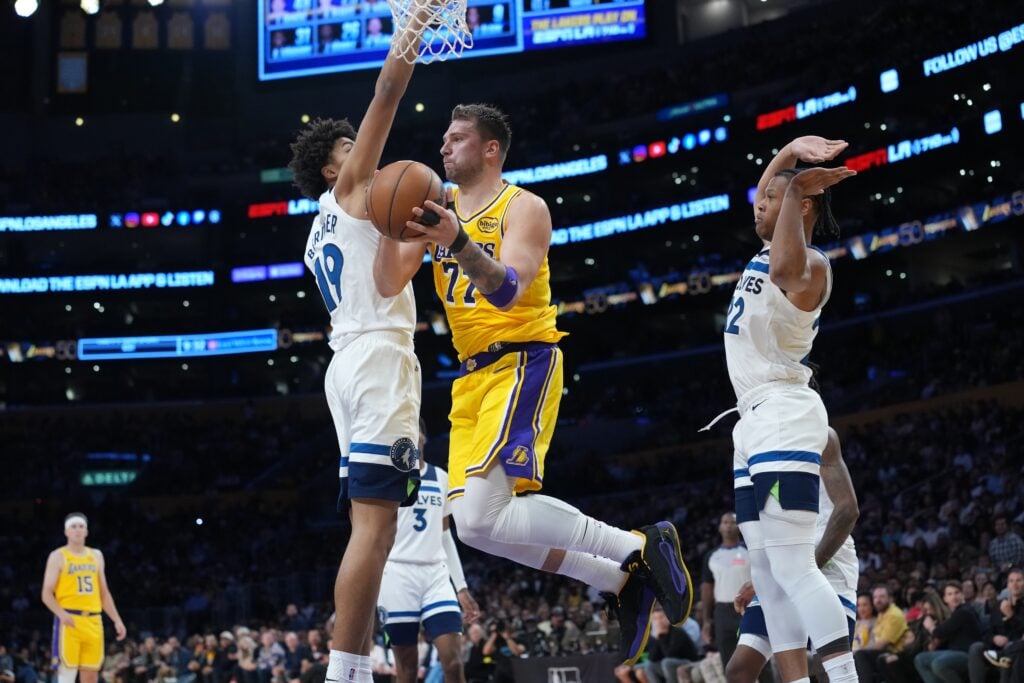 Oct 24, 2025; Los Angeles, California, USA; Los Angeles Lakers guard Luka Doncic (77) passes the ball against Minnesota Timberwolves forward Joan Beringer (19) and guard Jaylen Clark (22) in the second half at Crypto.com Arena. Mandatory Credit: Kirby Lee-Imagn Images