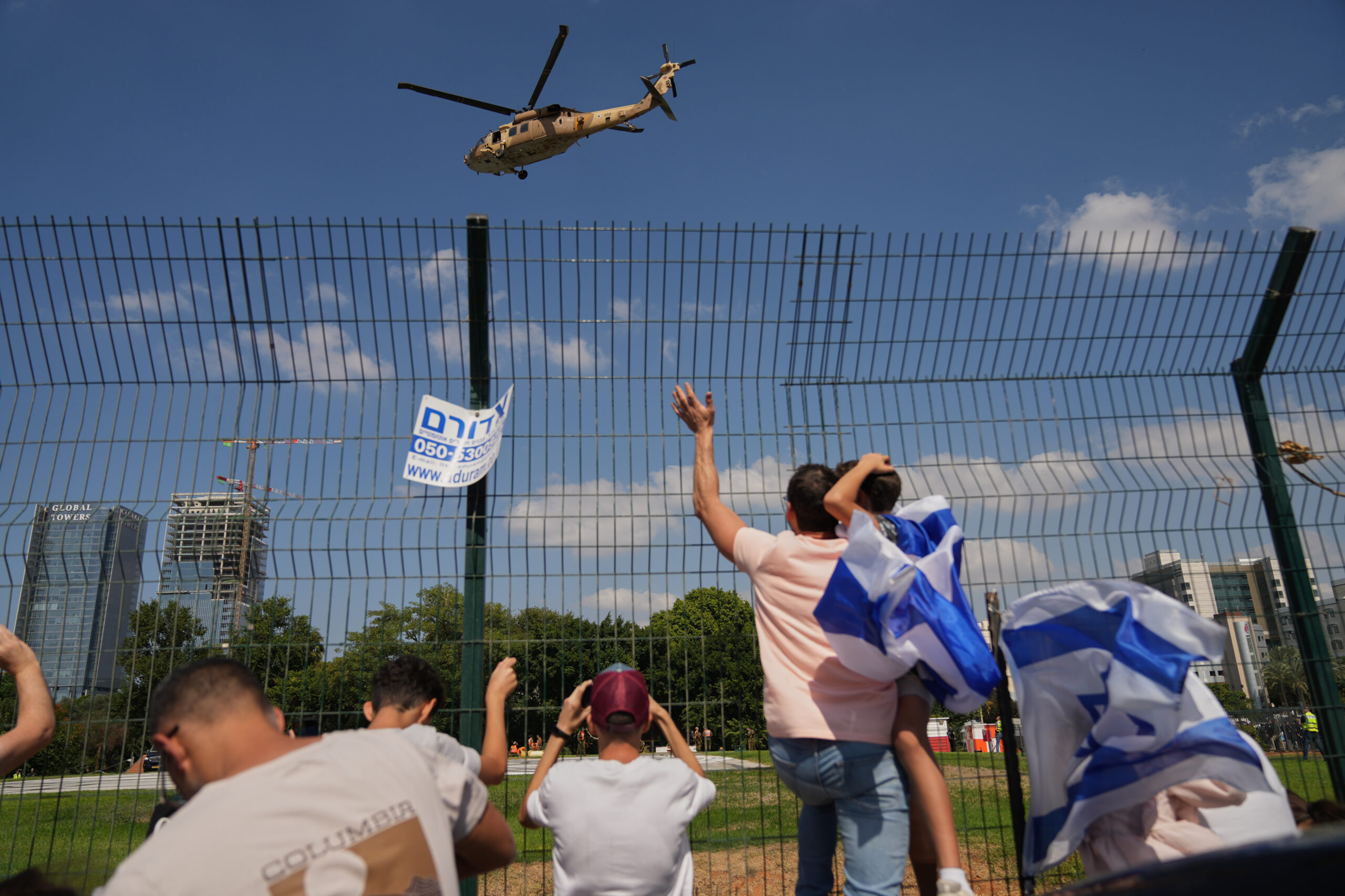 People watch a military helicopter carrying Israeli freed hostages as...