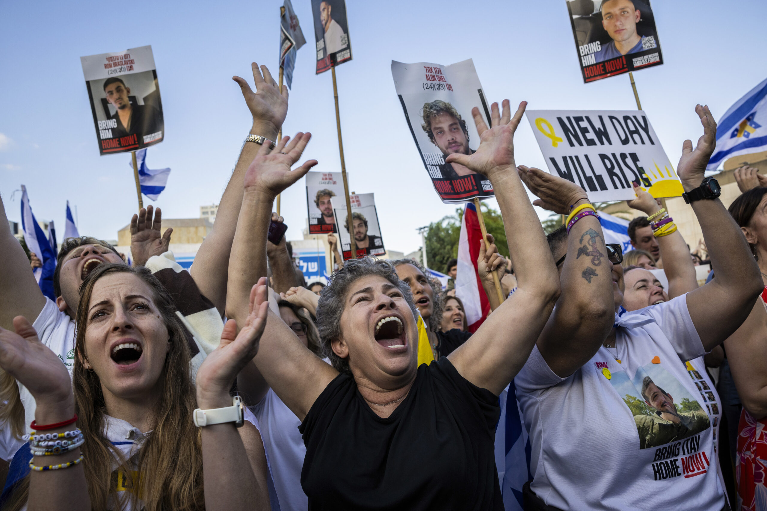 People react as they watch a live broadcast of hostages...