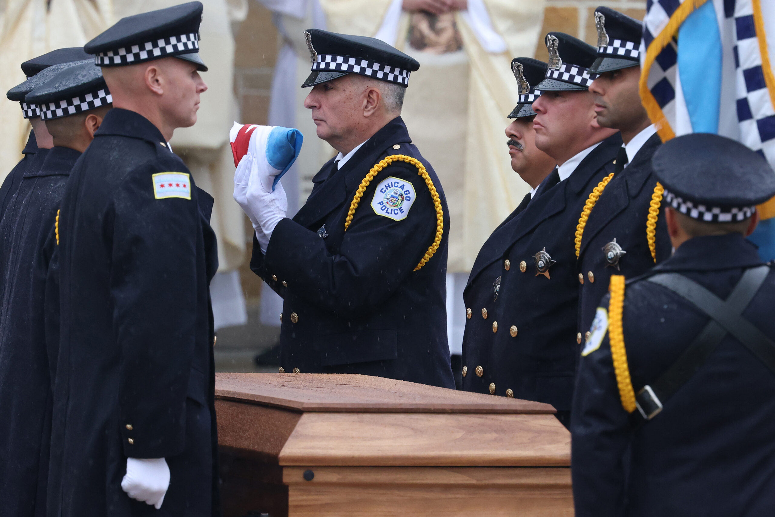 A Chicago flag is folded as pallbearers prepare to carry...