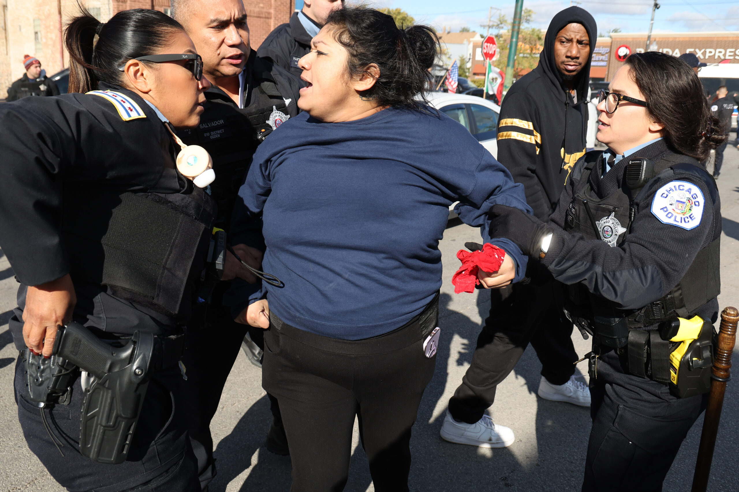 A woman is held by police as angry crowds of...
