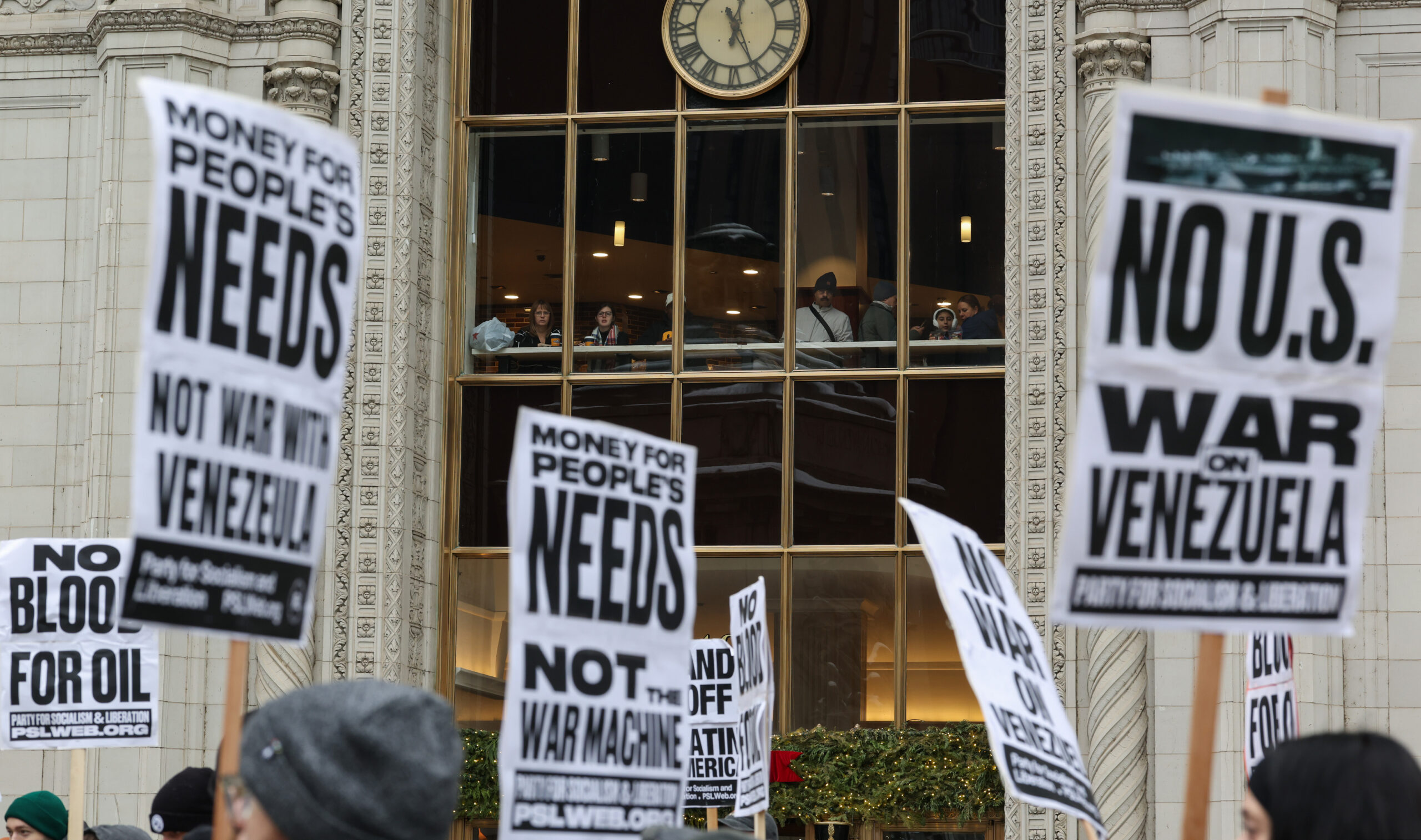 People in a second-floor cafe watch as demonstrators decry recent...