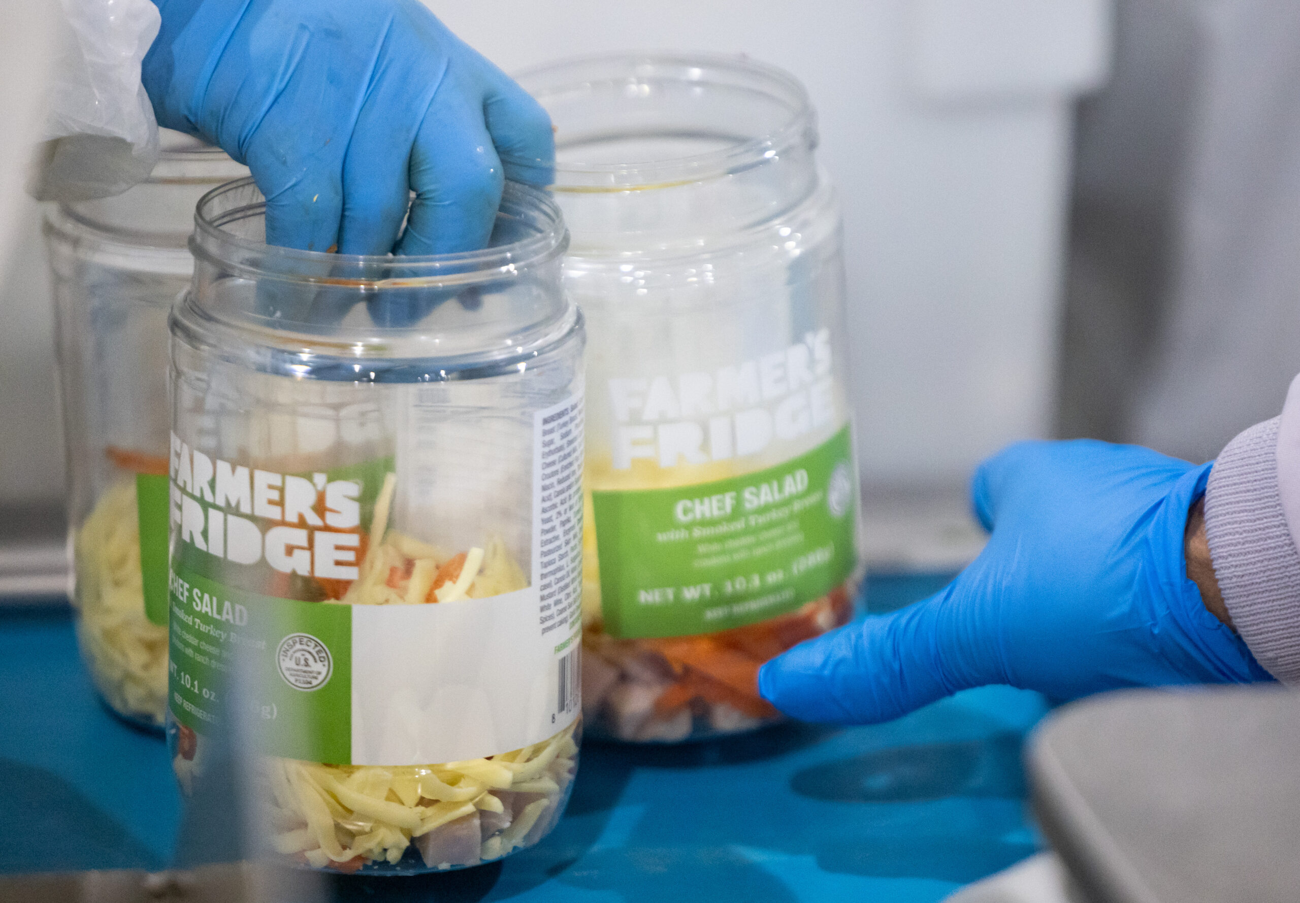 An employee hands off chef salad containers after loading them...