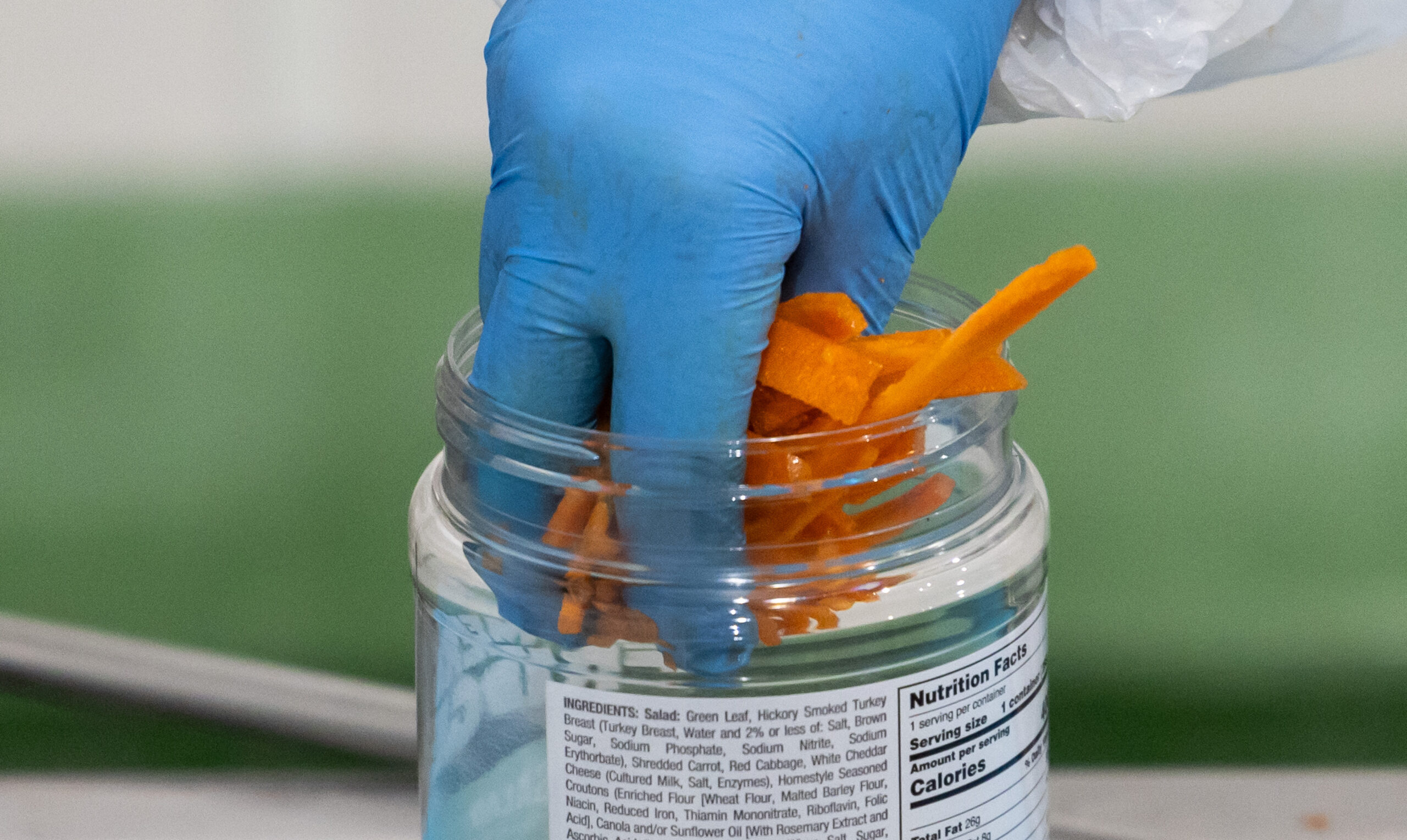 An employee loads carrots and cheese into a chef salad...