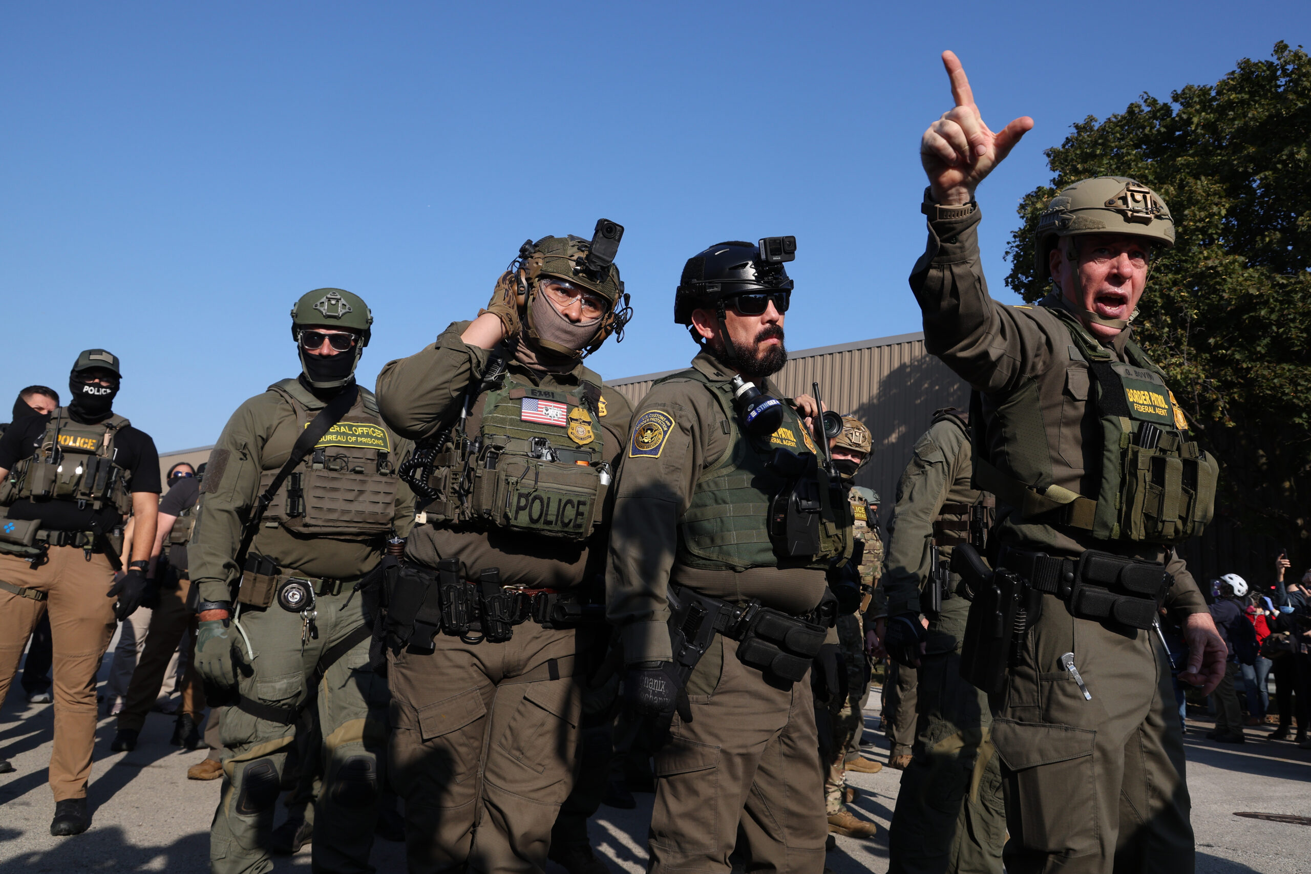 U.S. Border Patrol chiefÂ Gregory Bovino, right, warns protesters near the...