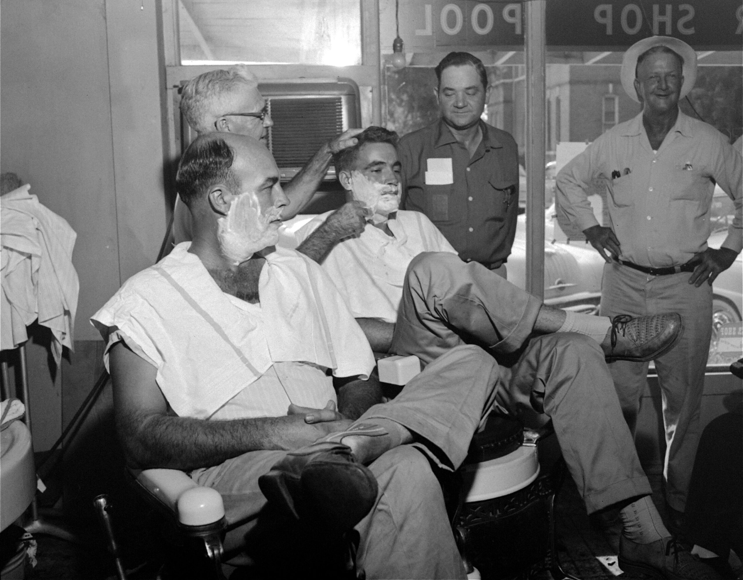 John W. Milam, 36, seated left, relaxes while barber J.J....
